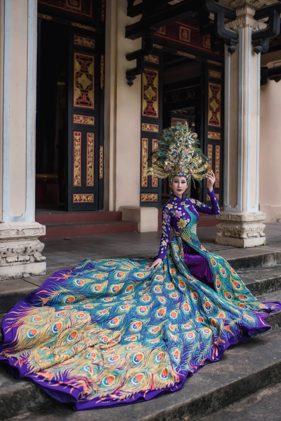 Được biết, tổng khối lượng bộ trang phục nặng xấp xỉ 20 kg, trong đó phần tà áo được may bằng vải lụa mượt mà màu xanh biển pha lẫn sắc tím hoàng tộc. Hình ảnh chim khổng tước biểu tượng của cuộc sống gia đình trọn vẹn, hôn nhân hạnh phúc, công danh giàu có, sung túc được thêu tỉ mẩn, kết cườm chạy dọc từ thân áo xuống đuôi tà áo và được vẽ phác họa bởi 99 lông công mềm mại, uyển chuyển.