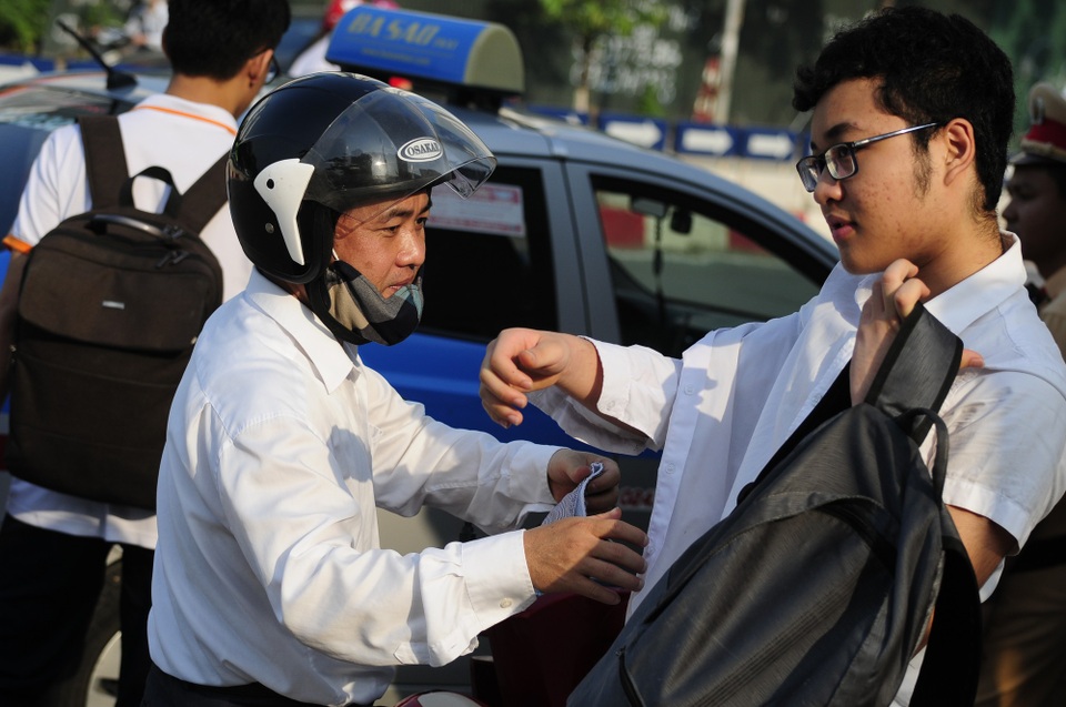 Bố cởi áo chống nắng giúp con trai kịp giờ thi.