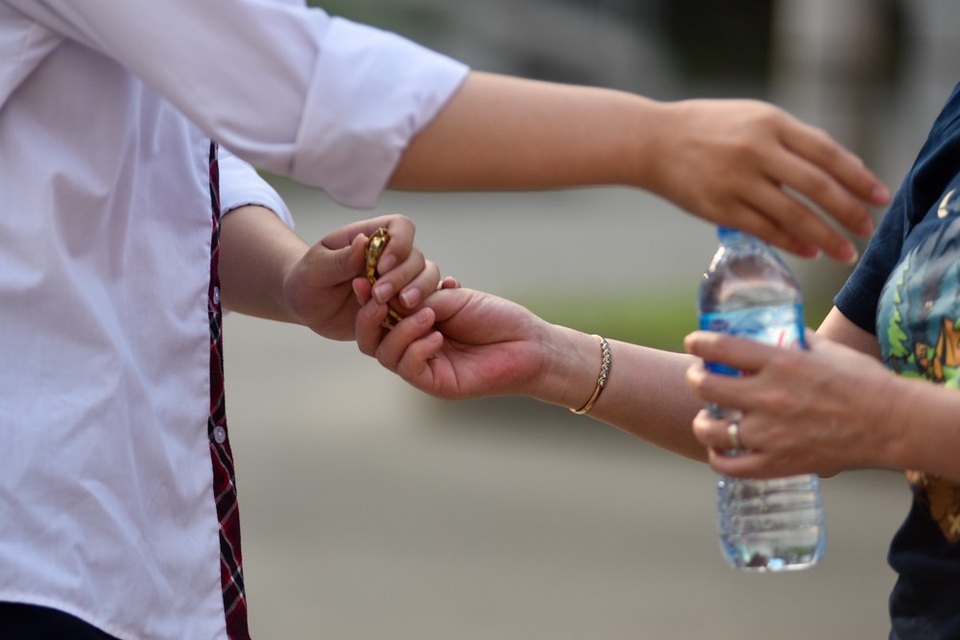 
Một phụ huynh không quên chuẩn bị nước và đồng hồ cho con trước khi vào phòng thi.
