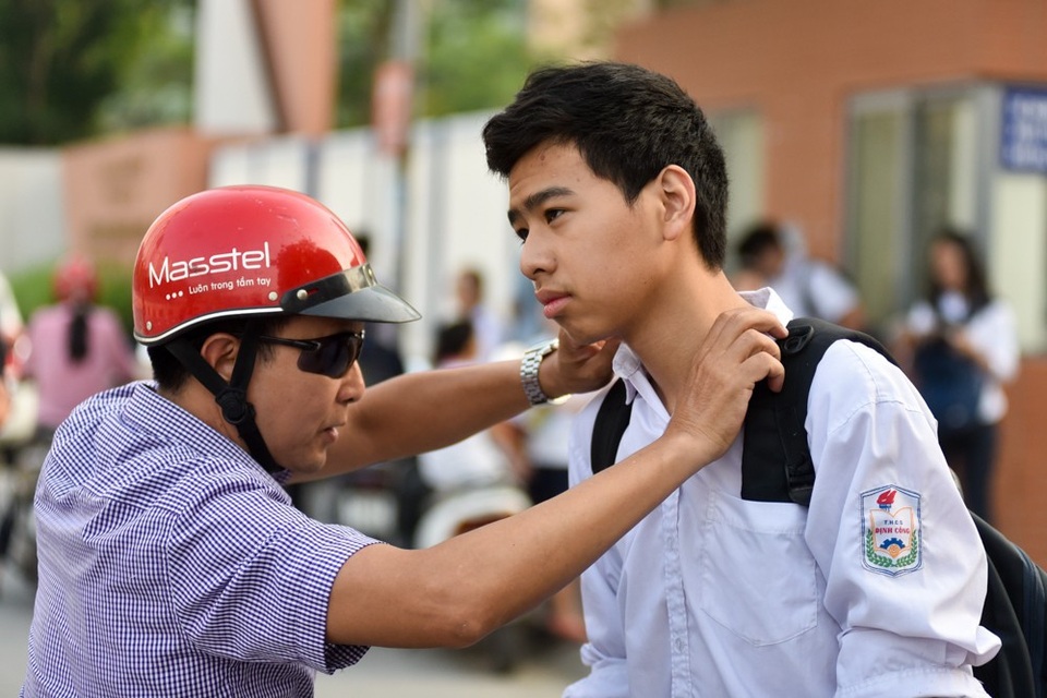 
Một phụ huynh chỉnh lại trang phục cho con trước khi ra về. (Ảnh: Toàn Vũ)
