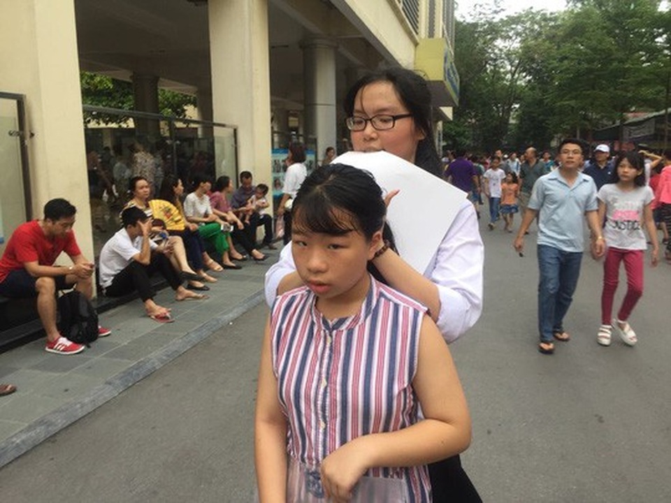 Chen chân thi vào lớp 6 Trường Nguyễn Tất Thành: 1 chọi 11 - 5 Dù đã sát giờ vào phòng thi nhưng một tình nguyện viên là học sinh của trường vẫn buộc tóc cho một thí sinh trước khi bước vào kỳ thi quan trọng.