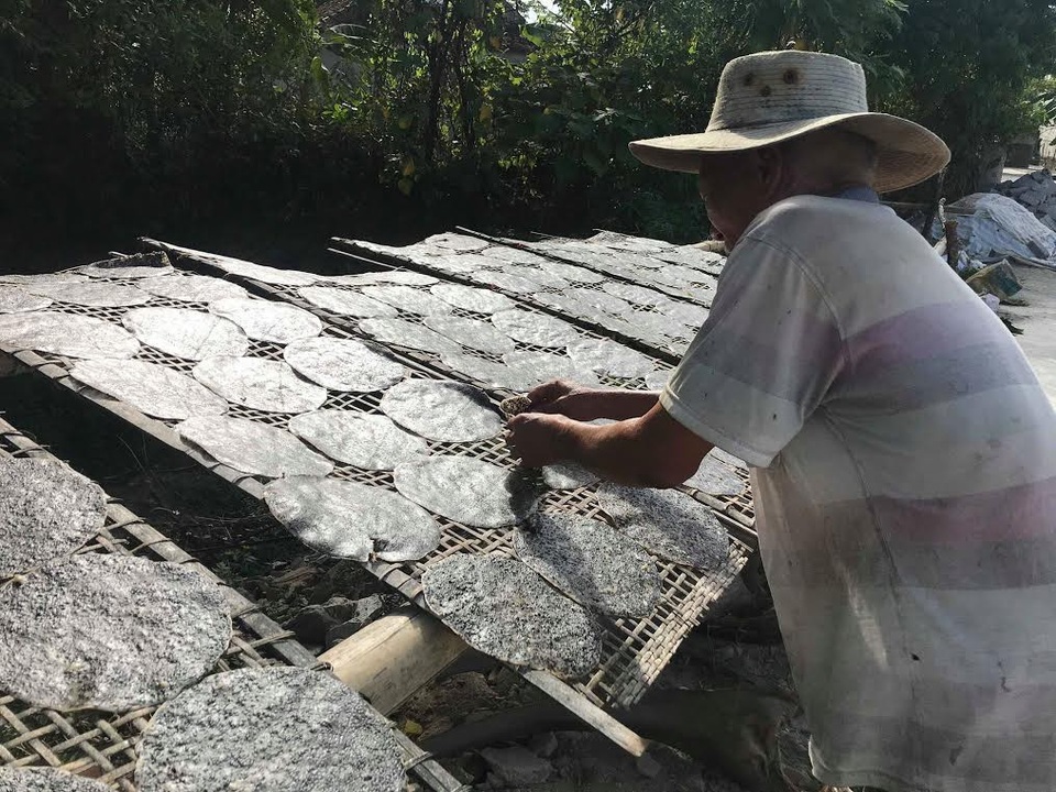 Làng nghề bánh đa ở xứ Nghệ vẫn luôn đỏ lửa giữa trời nắng 40 độ C - 3 Dưới nắng nóng hơn 40 độ C, bà con vẫn luôn tay trở đều từng chiếc bánh để bánh được khô đều, không bị cong vênh. Ảnh: Mỹ Hà