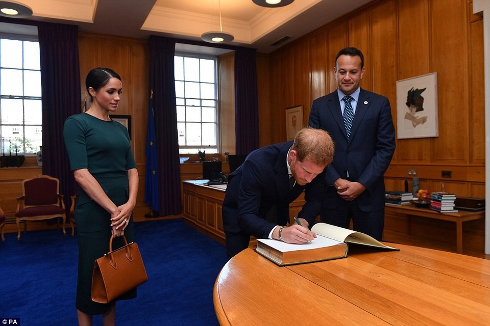 Công nương Meghan cuốn hút với phong cách thanh lịch khi công du nước ngoài - 4 Vợ chồng Hoàng tử Harry ký vào cuốn sổ lưu niệm tại tòa nhà chính phủ Ireland. (Ảnh: PA)