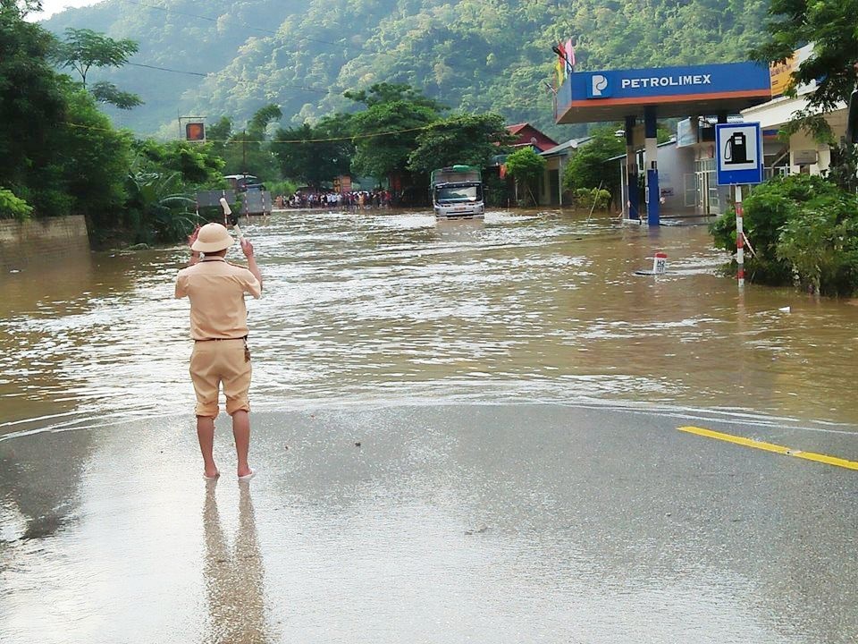 Thông tuyến Quốc lộ 6 đi các tỉnh Tây Bắc - 2 Cảnh sát giao thông hướng dẫn các phương tiện giao thông qua đoạn đường ngập sâu nước.
