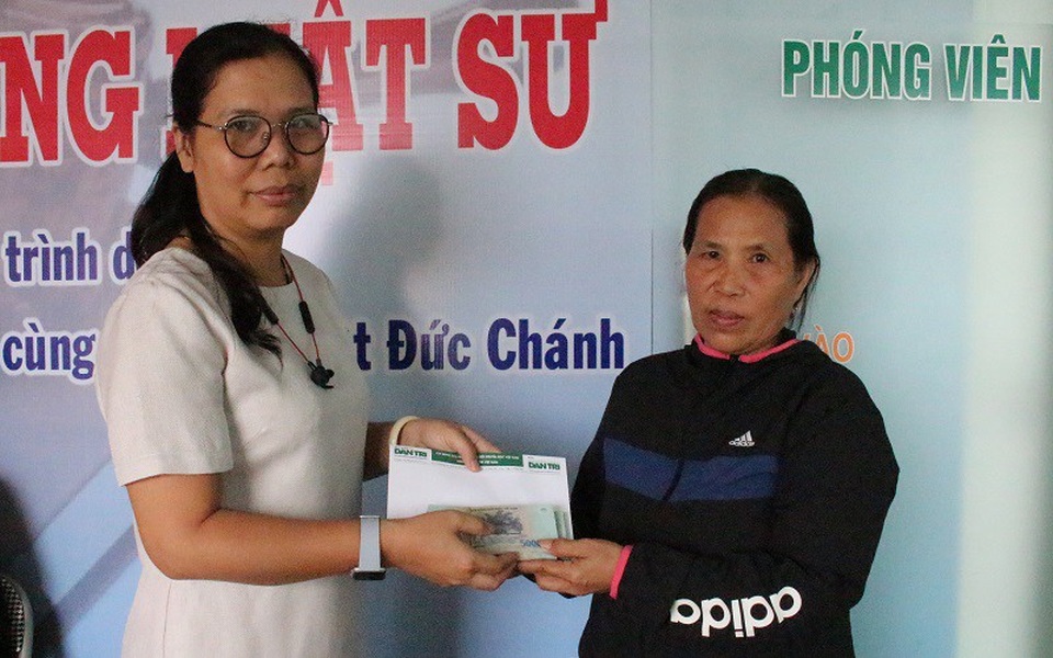 Nhà báo Toàn Thắng (bên trái) trao tiền bạn đọc giúp đỡ gia đình bà Bê