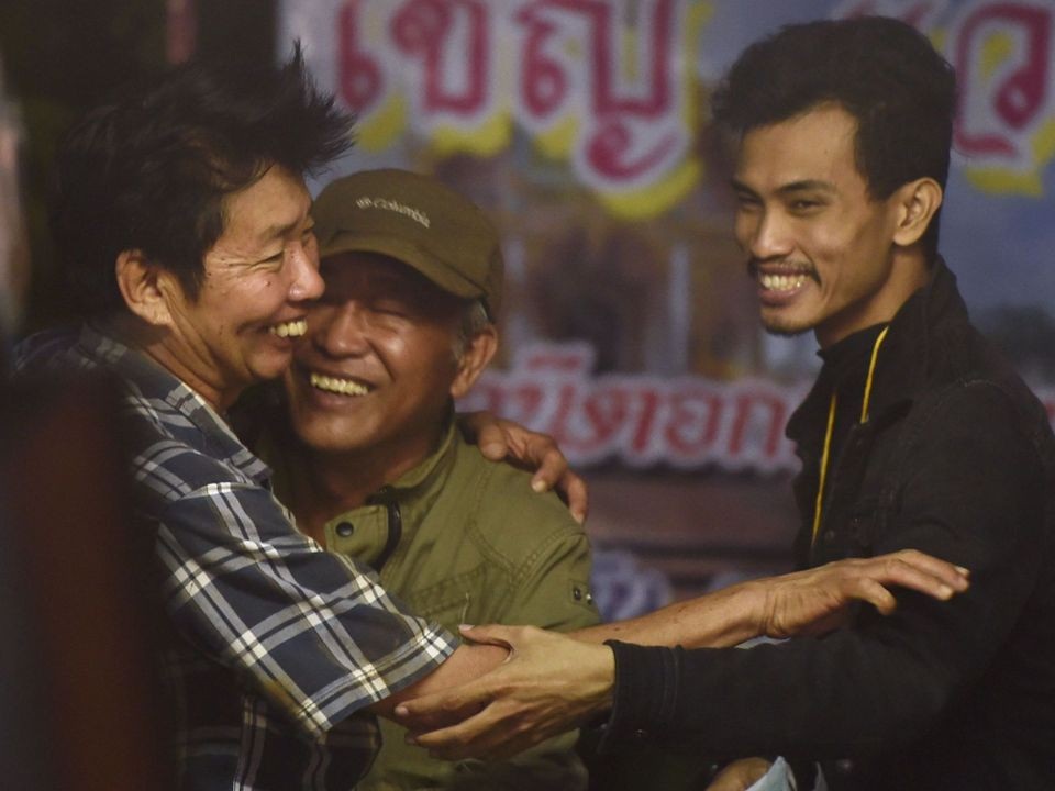 Người Thái vỡ òa hạnh phúc khi đội bóng mắc kẹt được tìm thấy còn sống - 1 Hơn một tuần qua, các thành viên trong gia đình của 13 người bị mắc kẹt, gồm 12 thành viên trong đội bóng thiếu niên Thái Lan và một huấn luyện viên, đã ngồi chờ bên ngoài cửa hang Tham Luang để trông ngóng tin tức về người thân của họ. Sau 9 ngày tìm kiếm, đội cứu hộ ngày 2/7 đã phát hiện vị trí của đội bóng và công bố những hình ảnh đầu tiên. Trong ảnh: Niềm vui của những người đàn ông là người thân của đội bóng thiếu niên Thái Lan khi nghe tin từ đội cứu hộ. (Ảnh: Sky)