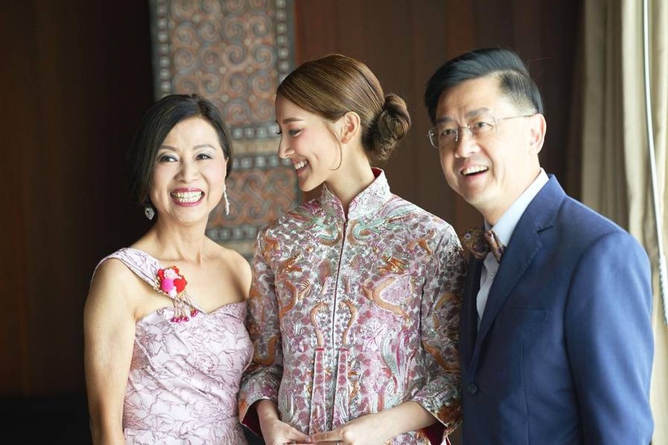 Trịnh Gia Dĩnh kết hôn với hoa hậu kém 22 tuổi - 11
Cô dâu chụp ảnh cùng bố mẹ ruột trong ngày trọng đại. Cô dâu Trần Khải Lâm sở hữu gia sản khổng lồ ít người biết. Bố của Trần Khải Lâm kinh doanh dầu mỏ, gia sản ước tính lên đến 1,5 tỷ đô la Hồng Kông (tương đương gần 4,5 ngàn tỷ đồng). Bên cạnh kinh doanh từ dầu mỏ, nhà họ Trần còn còn sở hữu chuỗi cửa hàng tiện lợi trị giá hàng trăm triệu đô la Hồng Kông cùng các công ty con rải rác mọi nơi. Vì thế, khi Khải Lâm bắt đầu hò hẹn Gia Dĩnh, gia đình cô phản đối vì khoảng cách tuổi tác lớn cũng như gia thế không tương xứng.
