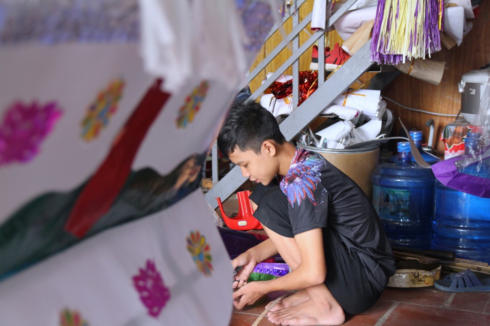 Thâm nhập thủ phủ sản xuất “osin, chân dài” cho người cõi âm - 3 Hoàng Quốc Cường (16 tuổi) đang bận rộn hoàn thiện các sản phẩm vàng mã để kịp đơn hàng giao cho khách. Theo Cường, không chỉ riêng dịp cúng “cô hồn” tháng 7 mà tất cả các tháng trong năm, người dân nơi đây đều tất bật với nghề trong đó chủ yếu là cung cấp đồ lễ cho việc hầu đồng, mở phủ, lập đàn và các tiệc hầu thánh.