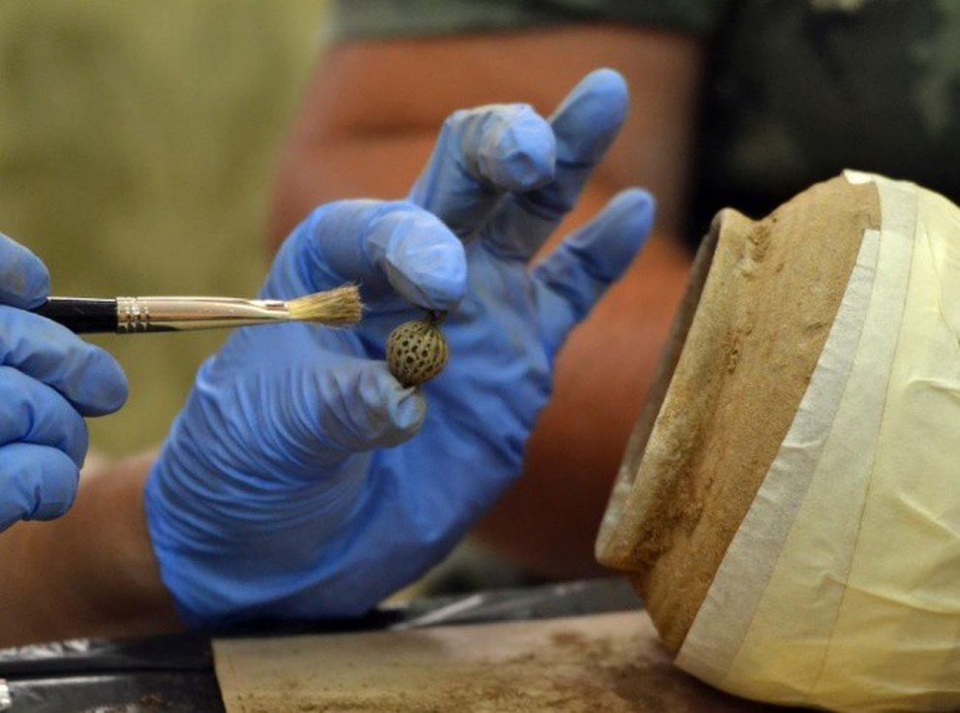 Các nhà khảo cổ học cẩn thận lấy từng đồ vật khỏi chiếc hũ kho báu.