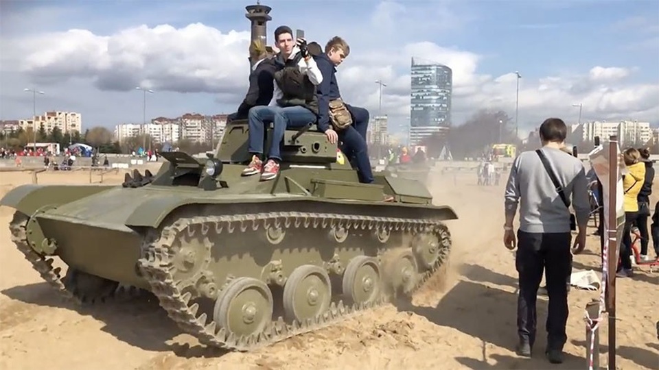 Sống sót thần kỳ khi bị xe tăng nặng 6 tấn chèn qua người - 1 Các nạn nhân ngồi trên xe tăng trước khi ngã xuống và bị xe chèn qua người (Ảnh: Ruptly)