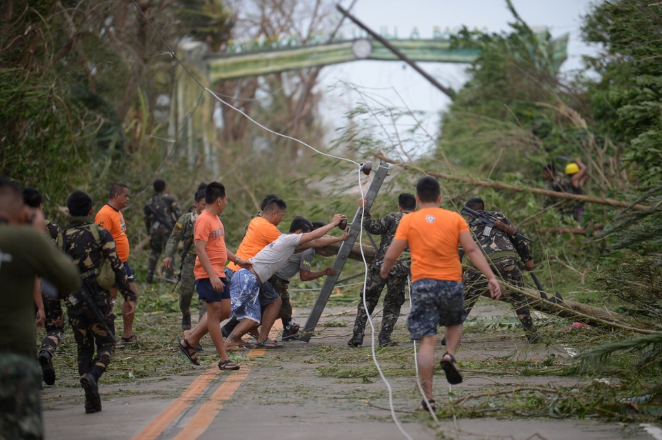 Hình ảnh đổ nát tại Philippines khi siêu bão lớn nhất trong năm càn quét - 1 Theo New York Times, sau 12 giờ bão Mangkhut đổ bộ vào Philippines, hiện đã có một trường hợp được ghi nhận là thiệt mạng. Giới chức Philippines vẫn chưa bắt đầu đánh giá thiệt hại do bão gây ra. Trong ảnh: Các nhân viên cứu hộ dựng lại các cây và cột điện bị đổ khi bão Mangkhut càn quét khu vực Baggao thuộc tỉnh Cagayan, phía bắc thủ đô Manila, Philippines sáng 15/9. (Ảnh: AFP)