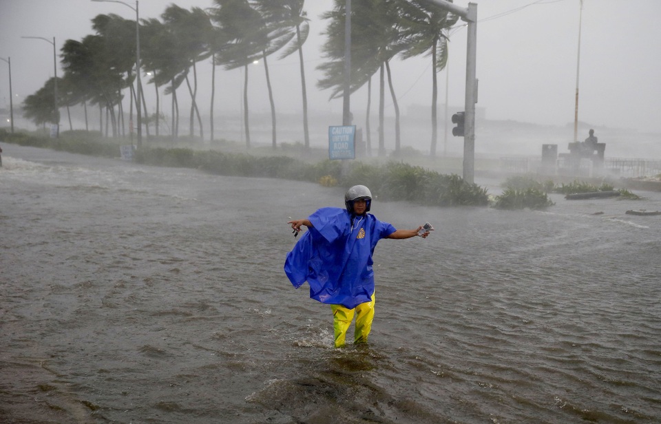 Hình ảnh đổ nát tại Philippines khi siêu bão lớn nhất trong năm càn quét - 8 Philippines đã huy động đông đảo các binh sĩ, cảnh sát và các đội cứu hộ để giúp người dân sơ tán và khắc phục hậu quả do bão Mangkhut gây ra. Trong ảnh: Cảnh sát giao thông hướng dẫn các phương tiện di chuyển trên đường ngập nước ở thủ đô Manila, Philippines. (Ảnh: Bloomberg)