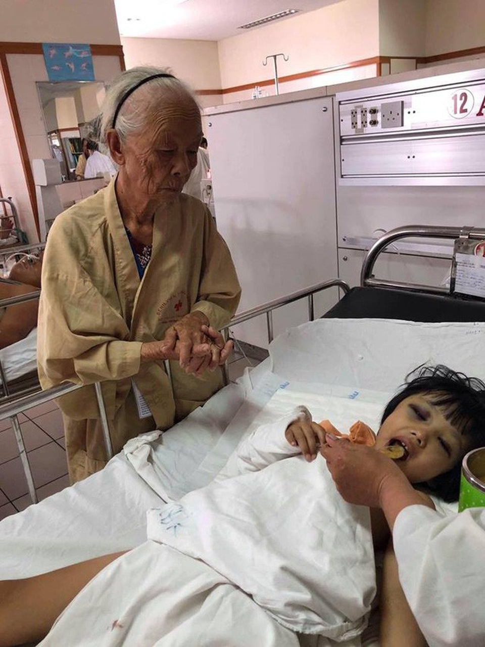 Sự hồi sinh kỳ diệu của bé gái 6 tuổi trong tình trạng nguy kịch - 1 Bé Thu Trâm được cụ Cẩm 78 tuổi chăm sóc trong bệnh viện. Ảnh: Uyển Hương