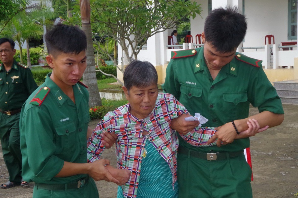 Các chiến sĩ bộ đội biên phòng giúp đỡ người bệnh đến nơi khám bệnh và nhận quà