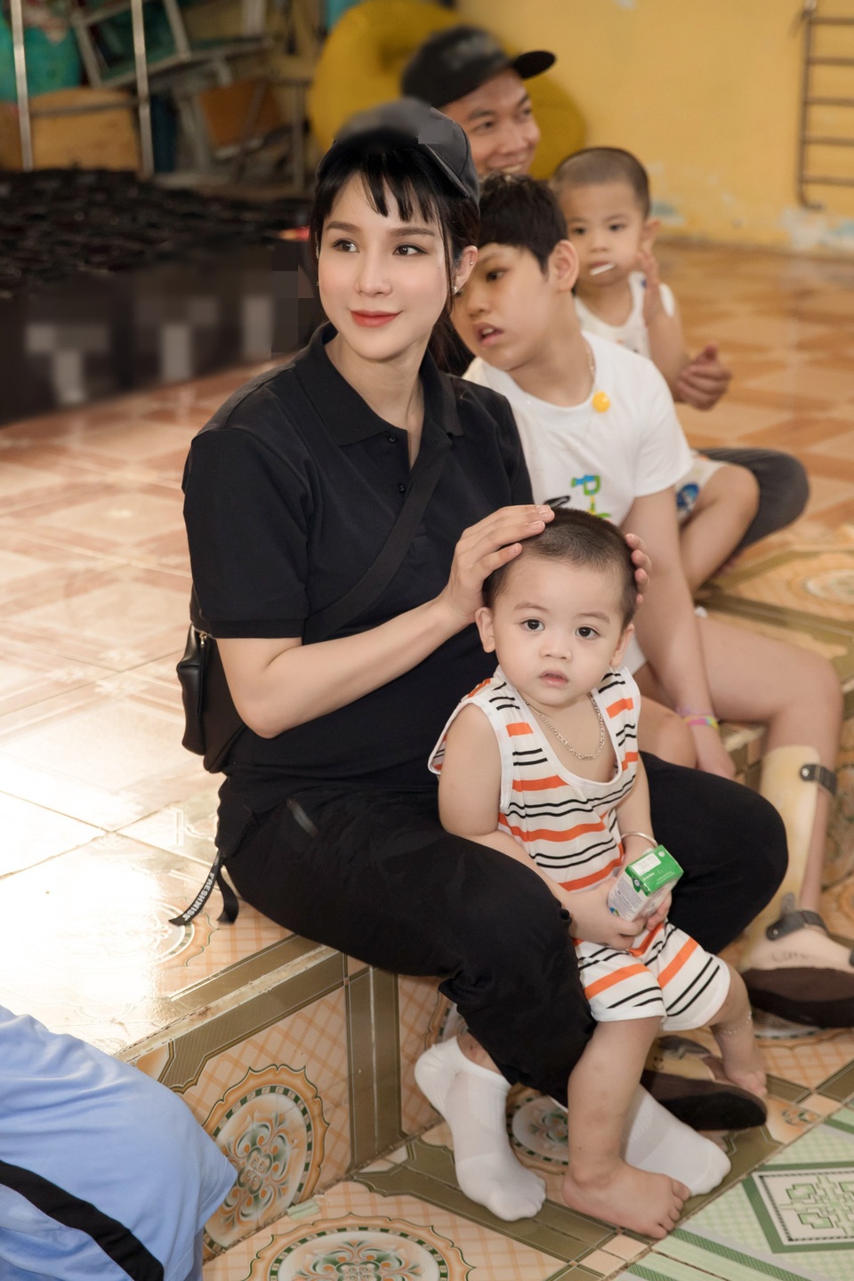 Diệp Lâm Anh diện trang phục áo thun đen, quần hộp giản dị nhưng không kém phần năng động đi trao quà cho các em nhỏ.