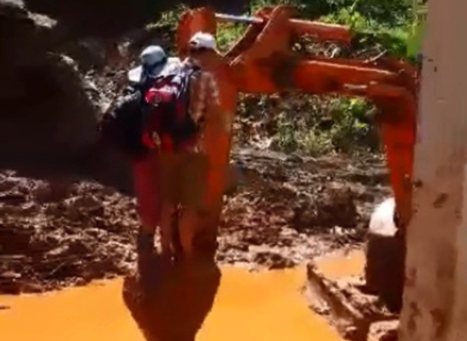 Giáo viên bám gàu máy xúc vượt điểm sạt lở đến trường trước ngày khai giảng - 1 Thầy cô giáo đu gàu máy xúc qua điểm sạt lở (Ảnh cắt từ clip)