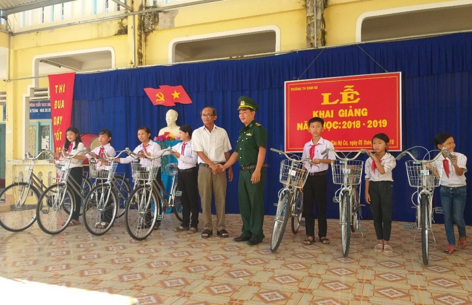 Đại diện lãnh đạo Đồn Biên phòng cửa khẩu quốc tế Dinh Bà và xã Tân Hộ Cơ trao xe đạp cho học sinh
