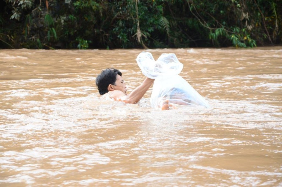 “Đến giáo viên cũng từng chui túi nilon để vượt lũ”! - 1 Trưởng bản Vừ A Giống đang đưa một học sinh vượt lũ bằng túi (Ảnh: Đ. Tuấn).