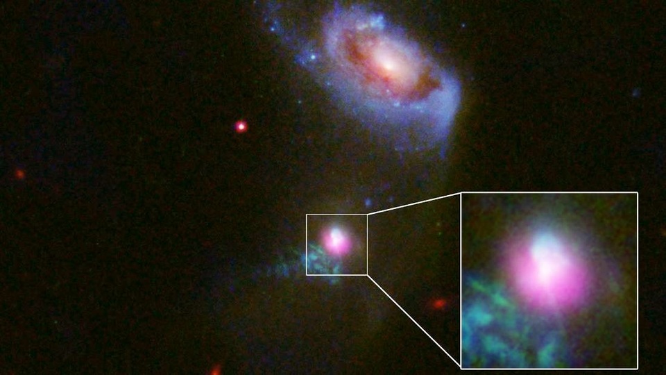 
Thiên hà SDSS J1354+1327 và thiên hà đồng hành ở phía trên. Sự thoát khí từ hố đen có màu tím - Ảnh của NASA, ESA và J.Comerford (Đại học Colorado, Boulder).
