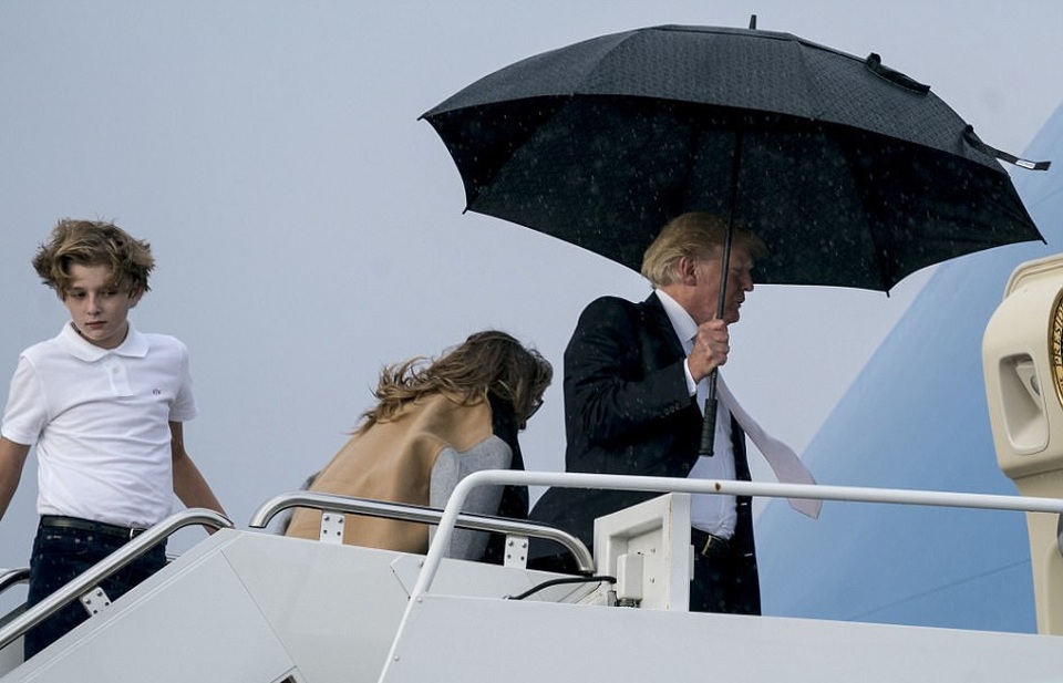 Tổng thống Trump che ô một mình, phu nhân và con trai đầu trần - 5 Gió lớn khiến Đệ nhất phu nhân Mỹ gặp khó khăn trong việc di chuyển. Bà Melania được nhìn thấy cúi người về phía trước. (Ảnh: Dailymail)