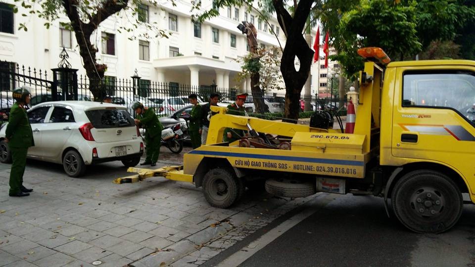 Lực lượng chức năng xử lý những ô tô đỗ ở bãi xe không phép.