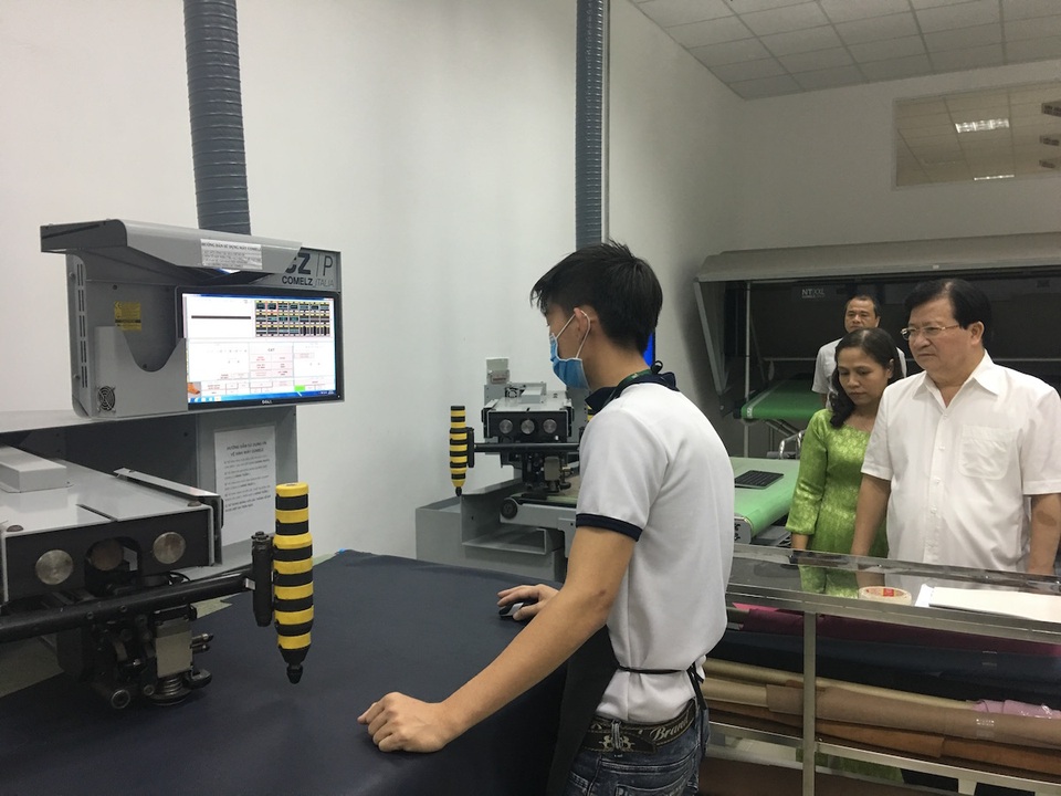 Phó Thủ tướng Trịnh Đình Dũng (phải) theo dõi một công đoạn trong dây chuyền sản xuất da giày, túi xách