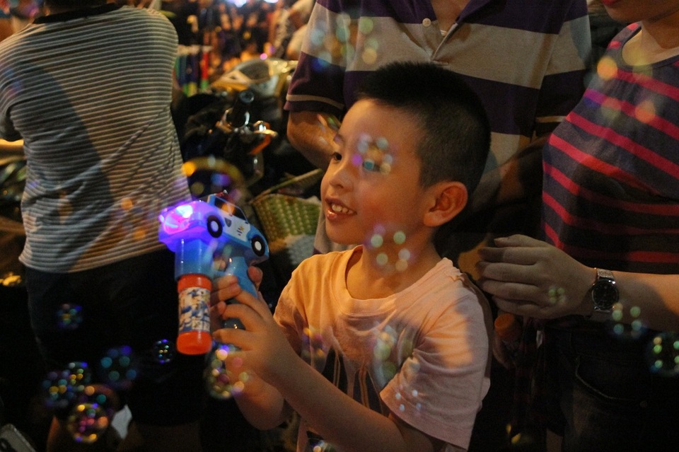 
Một em nhỏ hào hứng chơi trò bắn súng bóng trong không gian đi bộ ở phố Hàng Mã
