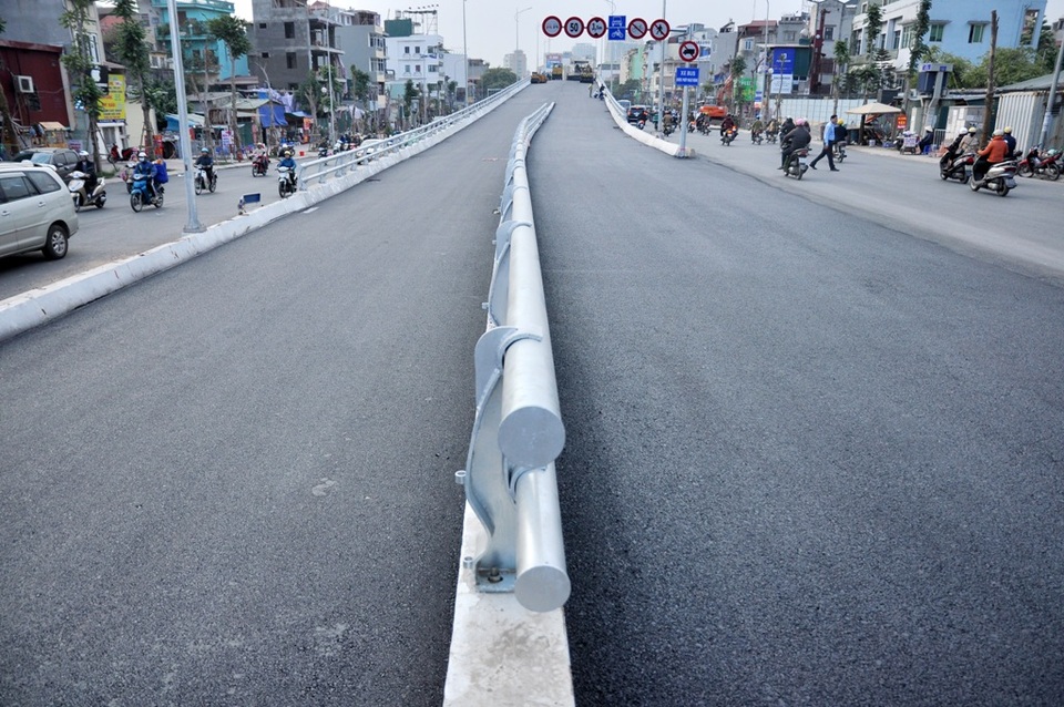 Mặt cầu rộng 12m đang được tiến hành trải nhựa nhẵn đồng thời sơn kẻ vạch giao thông, phân luồng cho các phương tiện lưu thông trên cầu