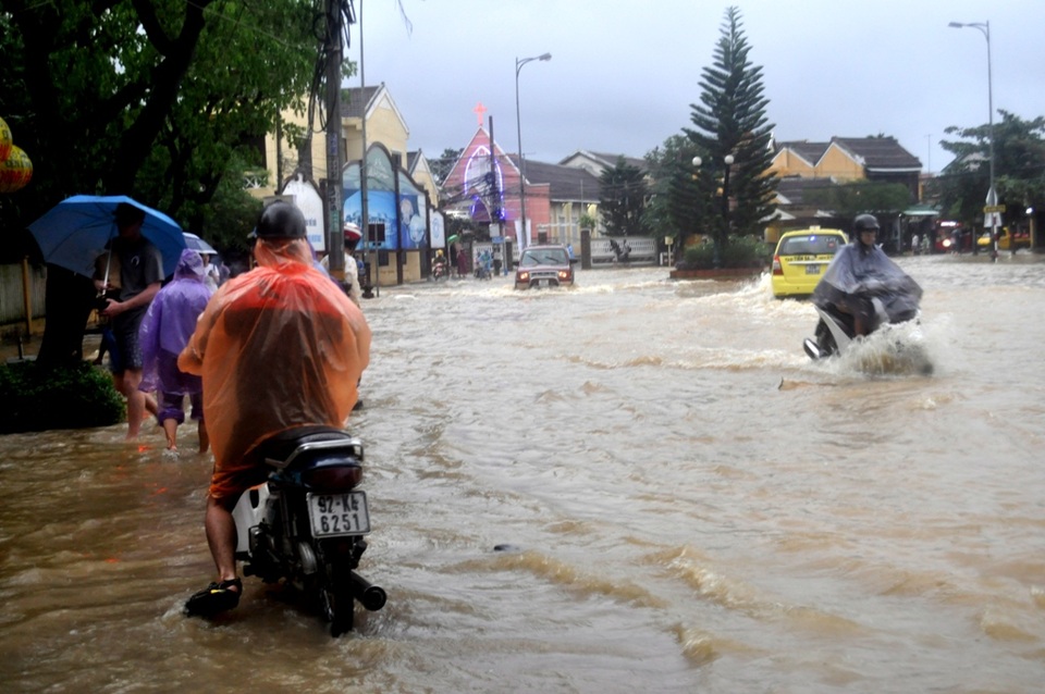 Người dân phố cổ Hội An đi lại khó khăn vì nước dâng cao bất thường, nhiều người bất chấp nguy hiểm đi lại giữa nước sâu hoặc lên bờ lề để đi