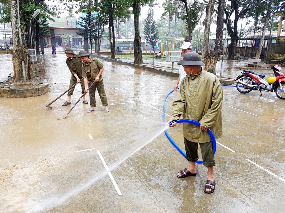 Dân quân, công an đội mưa cùng giáo viên giúp trường dọn lụt - 2 Lực lượng Công an xã Đại An giúp trường dọn bùn non trong sân trường