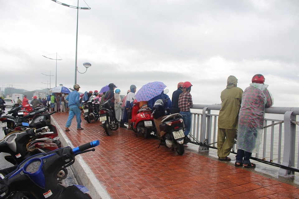 Khoảng 100 người vẫn đội mưa đứng trên cầu Trần Phú (Nha Trang) để theo dõi công tác tìm kiếm 2 cha con mất tích