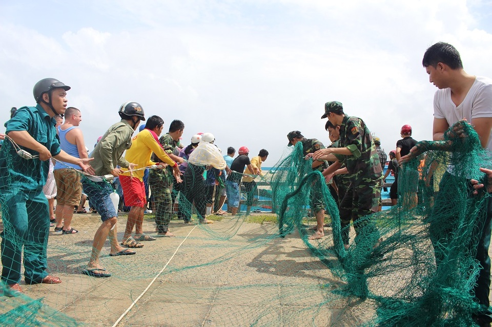 Các chiến sĩ giúp dân kéo lưới lên bờ giải cứu tàu cá mắc cạn