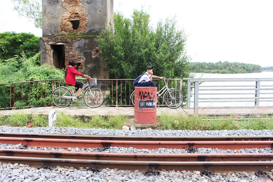 
Hai học sinh đang chờ cho tàu hỏa chạy qua để tiếp tục đến trường. Mong muốn của người dân lúc này là có một cây cầu kiên cố để không còn tình trạng con em đi học bằng thuyền, chui hầm tàu hỏa mỗi khi cầu gỗ bị cuốn trôi. Theo UBND xã Vĩnh Ngọc, quy hoạch xây cầu kiên cố đã có từ lâu nhưng hiện dự án vẫn đang còn trên giấy, chưa khởi động
