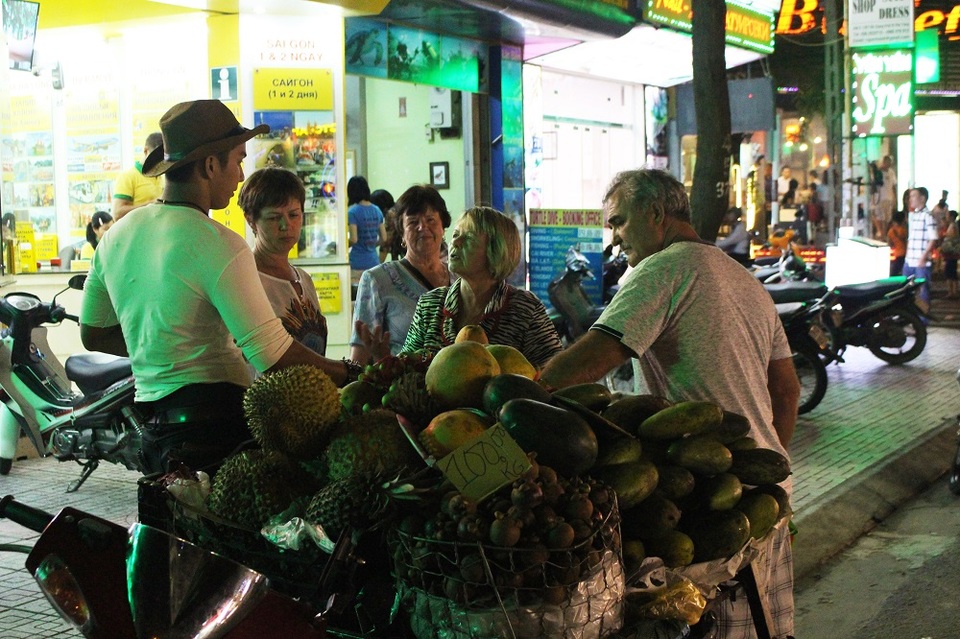 Du khách Nga tản bộ và dừng chân bên một gian hàng trái cây di động của một anh chàng cao bồi Việt Nam