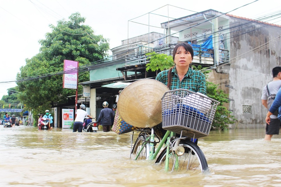 Một phụ nữ với vẻ mặt hốt hoảng khi vượt qua đoạn đường bị ngập lụt