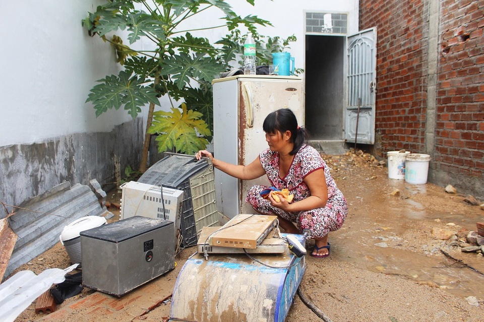 Chị Thảo bên đống tài sản hư hỏng do trận lũ vỡ kênh gây ra