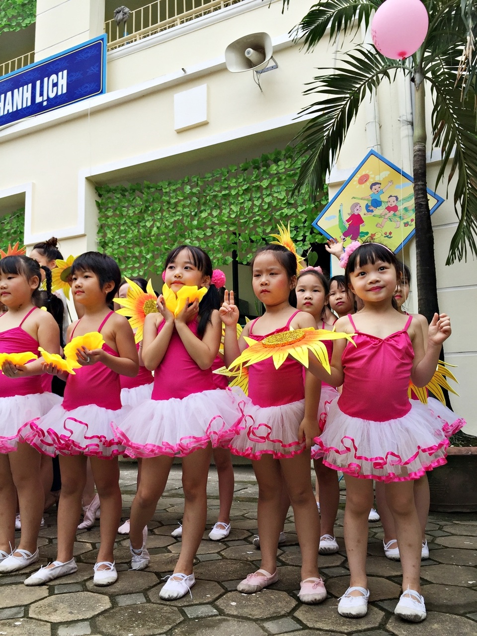 Em bé điệu đà trong sắc váy hồng và thích thú với trái bóng bay trên tay.