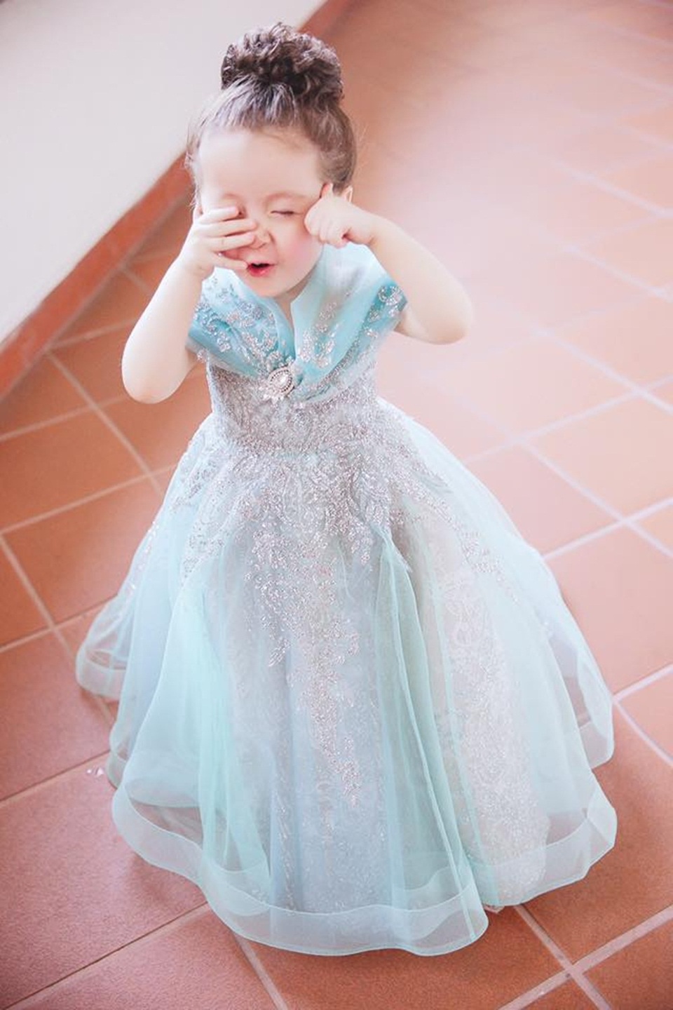 Cadie Mộc Trà “gây thương nhớ” khi hóa thành "công chúa Lọ Lem" - 7 Cadie được mẹ búi tóc cao. Biểu cảm từ ngơ ngác cho đến nụ cười đáng yêu, vẻ tự tin tạo dáng trốn tìm với người đối diện của “bà bán mì” khiến người xem không thể rời mắt.