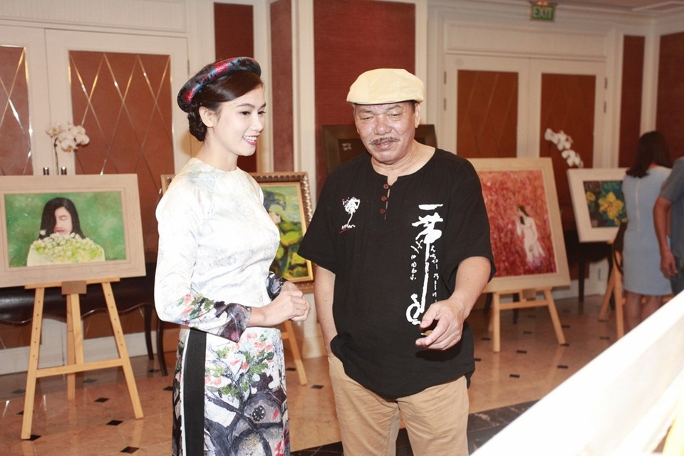 Nhạc sĩ Trần Tiến chia sẻ cảm xúc khi ngắm các bức tranh. Phía sau là hai bức vẽ lấy cảm hứng từ tình yêu áo dài của Lương Giang.