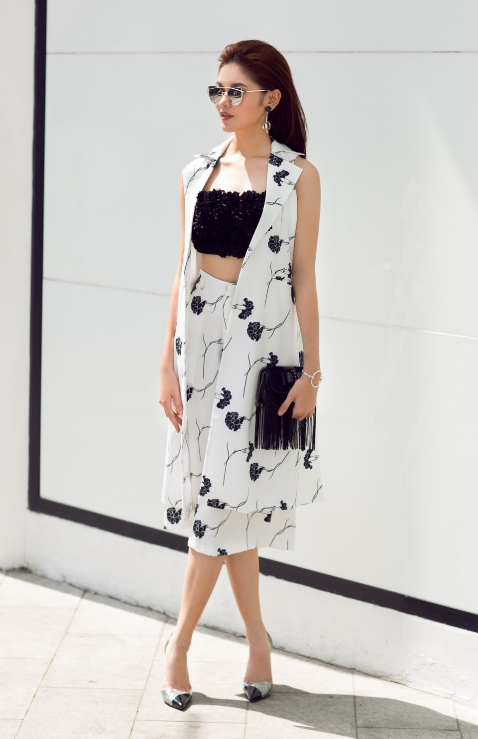 Thùy Dung tiếp tục khoe phong cách streetstyle với một thiết kế trắng - đen. Mốt áo blazer dáng dài không tay được cô tận dụng nhằm khiến vóc dáng trông thanh thoát hơn.