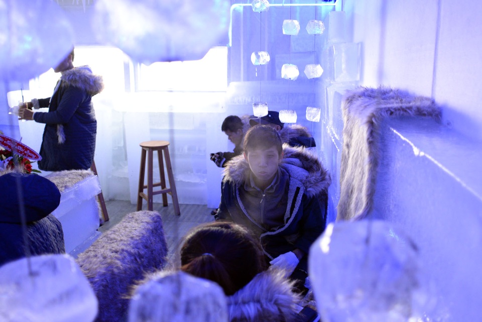 Một bạn nam thích thú phà hơi khói khi ngồi bên trong quán cà phê -10 độ C.