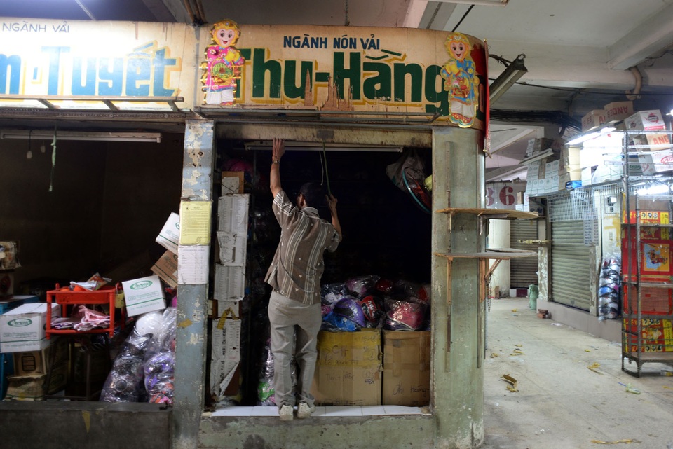 Tiểu thương di dời hàng hóa khỏi khu chợ cổ nhất Sài Gòn - 10 Ông Hoàng (56 tuổi) đã kinh doanh ở chợ hơn 20 năm nay đang kéo cửa đóng quầy đi gọi người dọn hàng phụ.