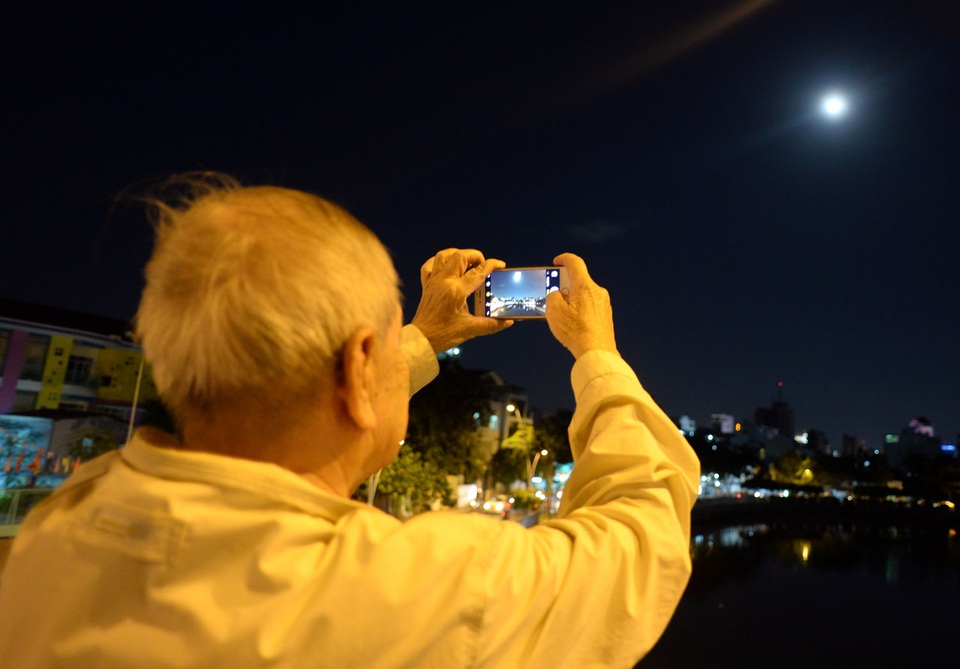 Ngắm siêu trăng trên bầu trời Sài Gòn - 8 Cụ Tám (68 tuổi, ngụ Phú Nhuận) thích thú dùng điện thoại chụp lại mặt trăng.