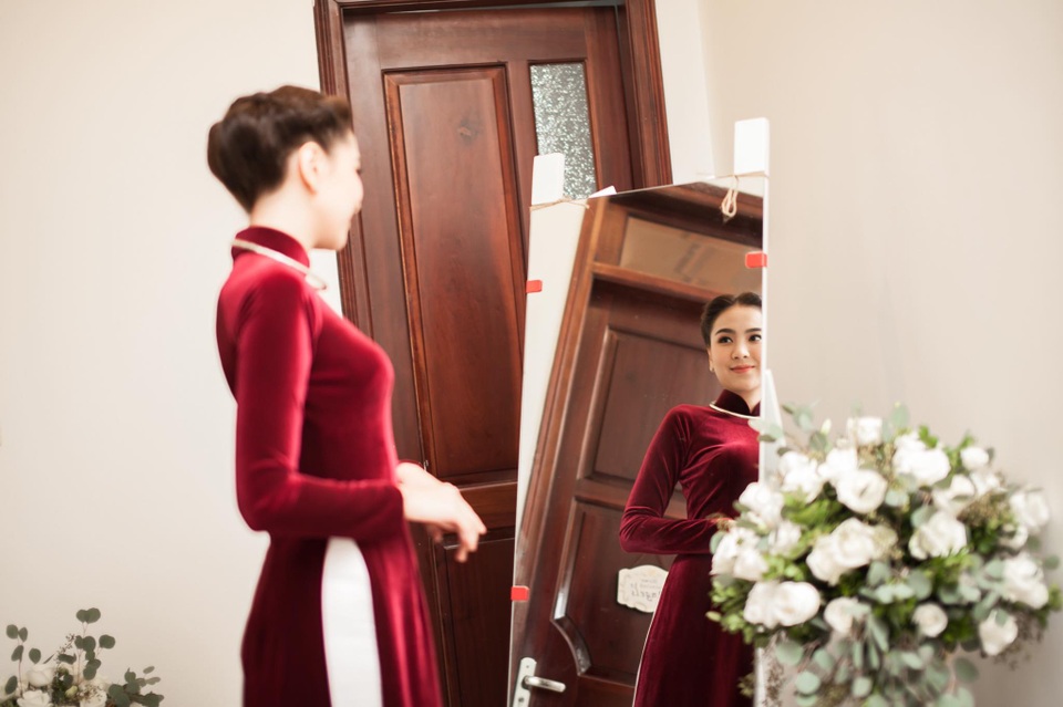 “Cô gái thời tiết” Mai Ngọc hôn chồng đắm đuối trong lễ ăn hỏi - 1 Mai Ngọc chọn bộ áo dài nhung the màu đỏ bordeaux phù hợp với tiết trời se lạnh ở Hà Nội. Chiếc áo dài đã làm nổi bật nhan sắc của Mai Ngọc trong ngày trọng đại của cuộc đời.