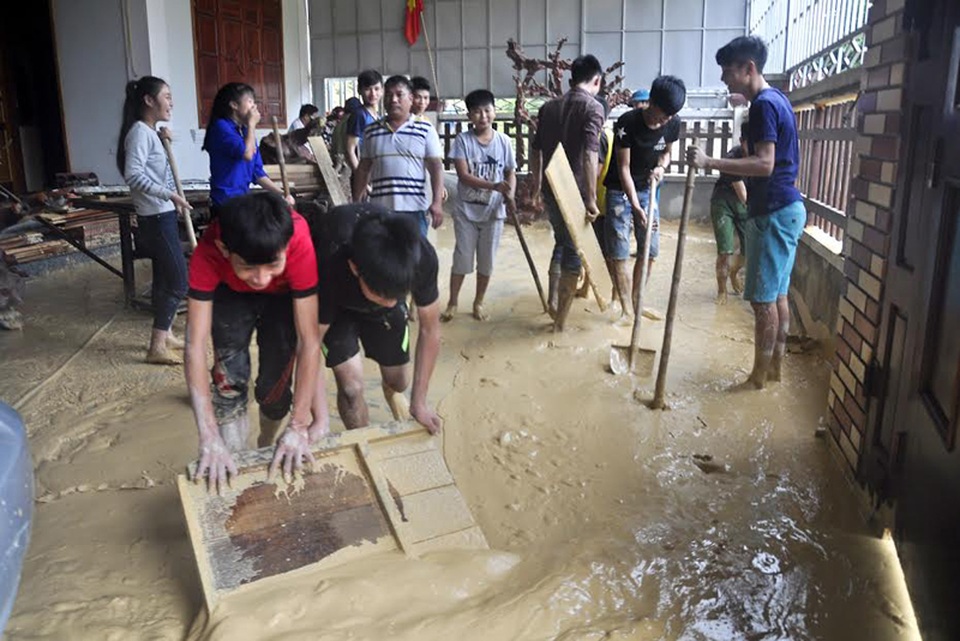 Giải cứu một gia đình mắc kẹt trong khối bùn đất từ trên núi ập xuống - 1 Đoàn viên thanh niên bốc dọn khối lượng bùn đất lớn tràn vào sân nhà ông Sỹ.