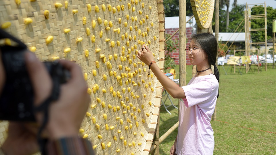 Tạo dáng bên nong tằm vàng óng được trung bày ở không gian hội chợ.