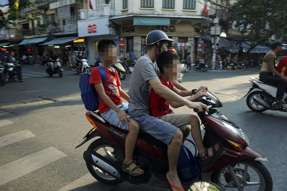 Nguy hiểm rình rập trẻ nhỏ không đội mũ bảo hiểm trên xe máy - 3
Hiện tượng chở hai, ba trẻ nhỏ không đội mũ bảo hiểm được nhìn thấy nhiều hơn tại những quận trung tâm thành phố như Hoàn Kiếm, Ba Đình. Các trường học khu vực này thường ở len lỏi trong các con phố cổ, khoảng cách đên trường gần khiến nhiều phụ huynh lơ là việc đội mũ bảo hiểm cho con em mình.