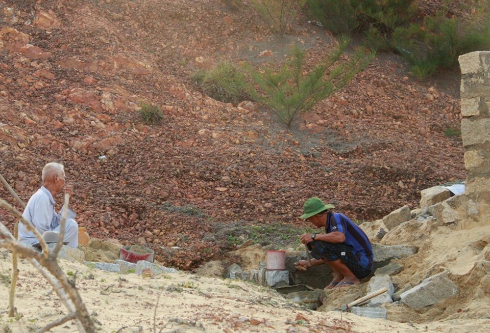 Người dân đang xây tường bao quanh chặn cát, đá bồi lấp vào mộ