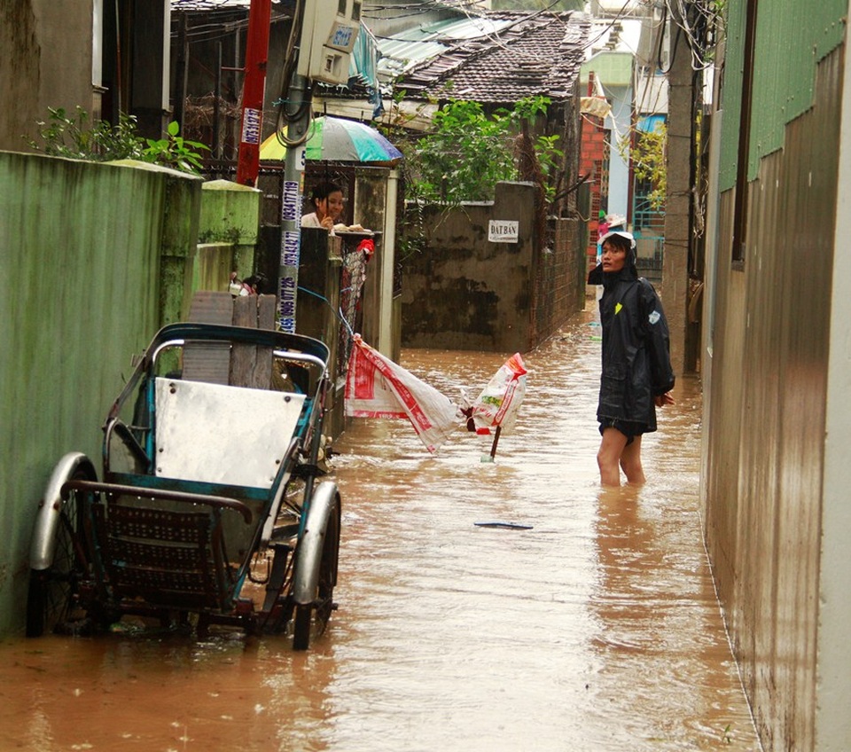 Dù trời mưa nhưng anh Thanh mặc áo mưa trong nước lạnh để cảnh báo người dân không đi vào khu vực có hố ga bị hư