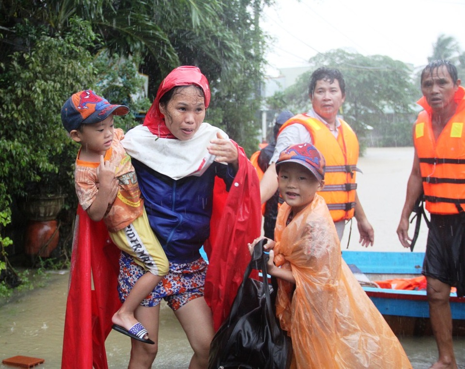 Chị Nhì tay bế con trai 5 tuổi vừa thoát khỏi nhà bị ngập nhưng vẫn lo đàn heo trong chuồng bị nước ngập